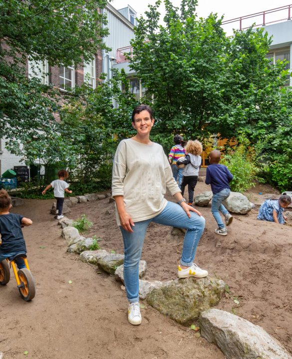 Schooldirecteur Annemarie van Oers en leerlingen op het nieuwe groenblauwe schoolplein.