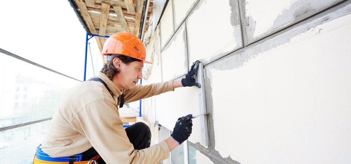 builder worker works with facade joint of building with plaster and spatula