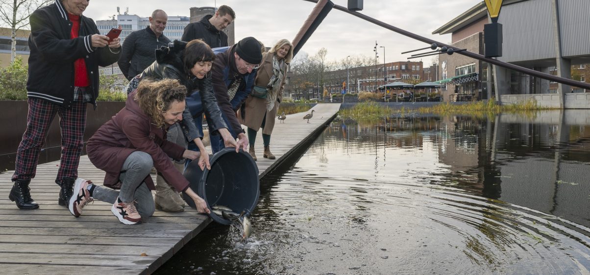 Het Nieuwe Instituut waar enkele personen de vissen in de vijver loslaten